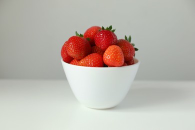 Fresh juicy strawberries in bowl on white table