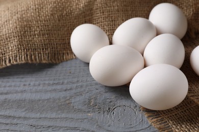 Photo of Fresh chicken eggs on grey wooden table, closeup. Space for text