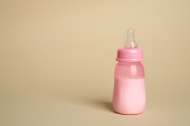 Feeding bottle with infant formula on beige background. Space for text