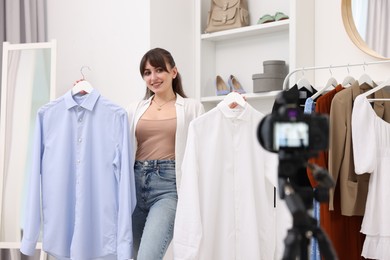 Photo of Smiling fashion blogger showing her clothes while recording video at home