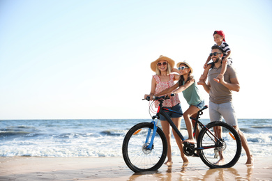 Happy family with bicycle on sandy beach near sea