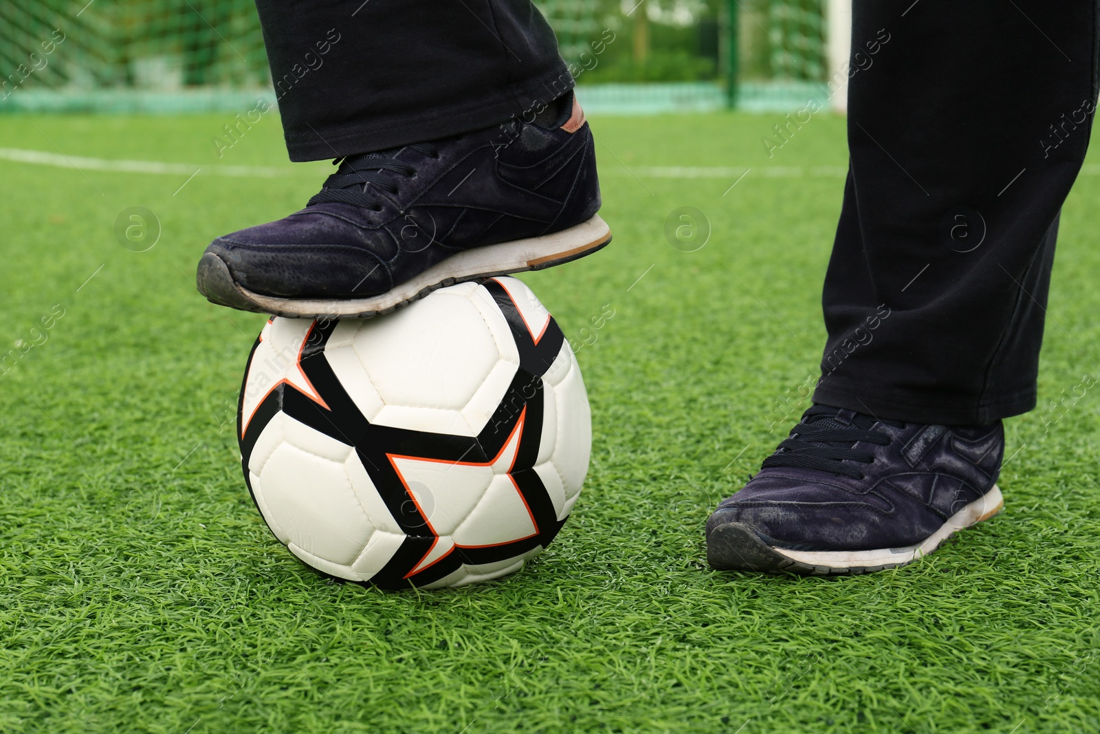 Photo of Man with soccer ball on green grass at stadium, closeup