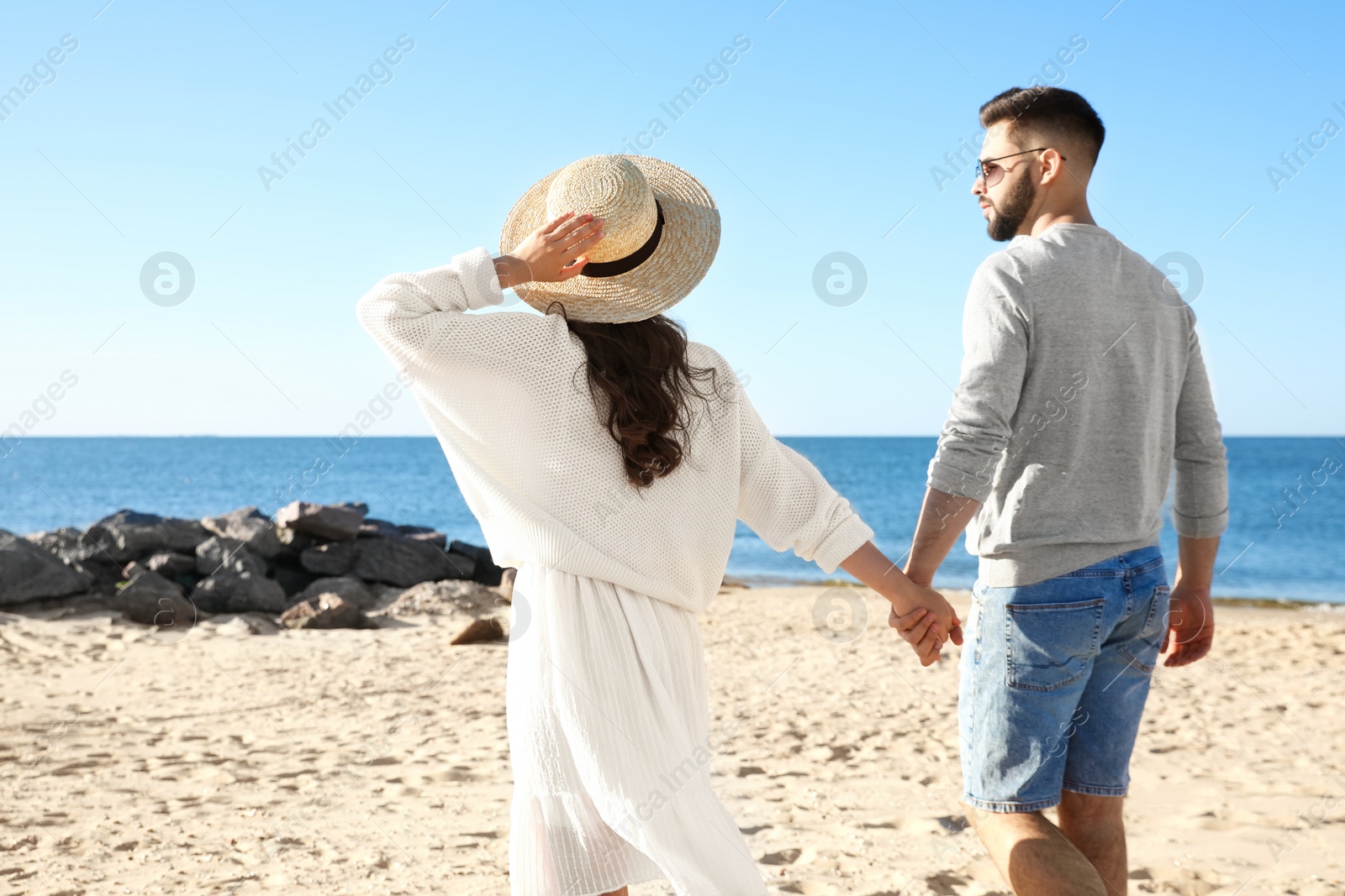 Photo of Happy young couple walking on beach near sea. Honeymoon trip