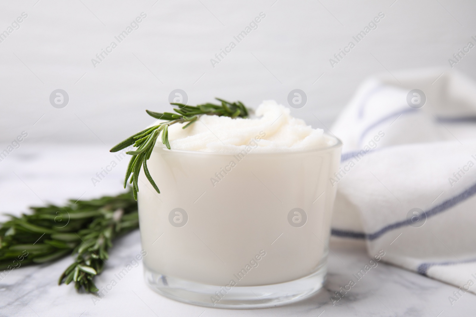 Photo of Delicious pork lard with rosemary in glass on white marble table, closeup