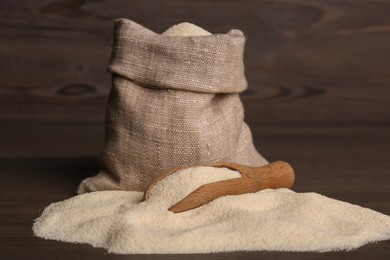 Photo of Bag and scoop with uncooked organic semolina on wooden table