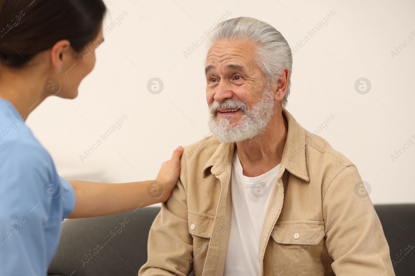 Photo of Health care and support. Nurse talking with elderly patient indoors
