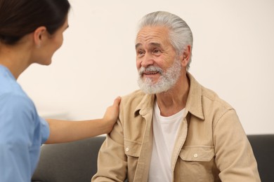 Photo of Health care and support. Nurse talking with elderly patient indoors