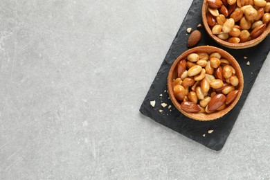 Photo of Tartlets with caramelized nuts on light grey table, top view and space for text. Tasty dessert