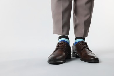 Photo of Man in stylish colorful socks, shoes and pants on white background, closeup. Space for text