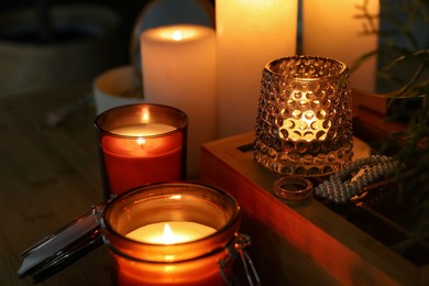 Photo of Lit candles on wooden dressing table in dark room