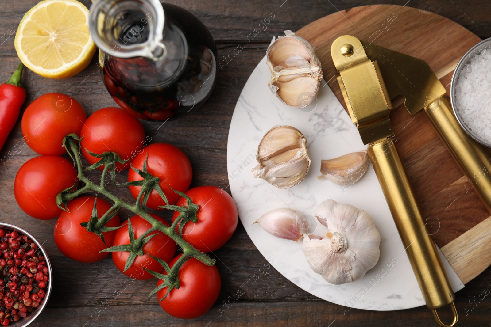 Photo of Different fresh ingredients for marinade and garlic press on wooden table, flat lay