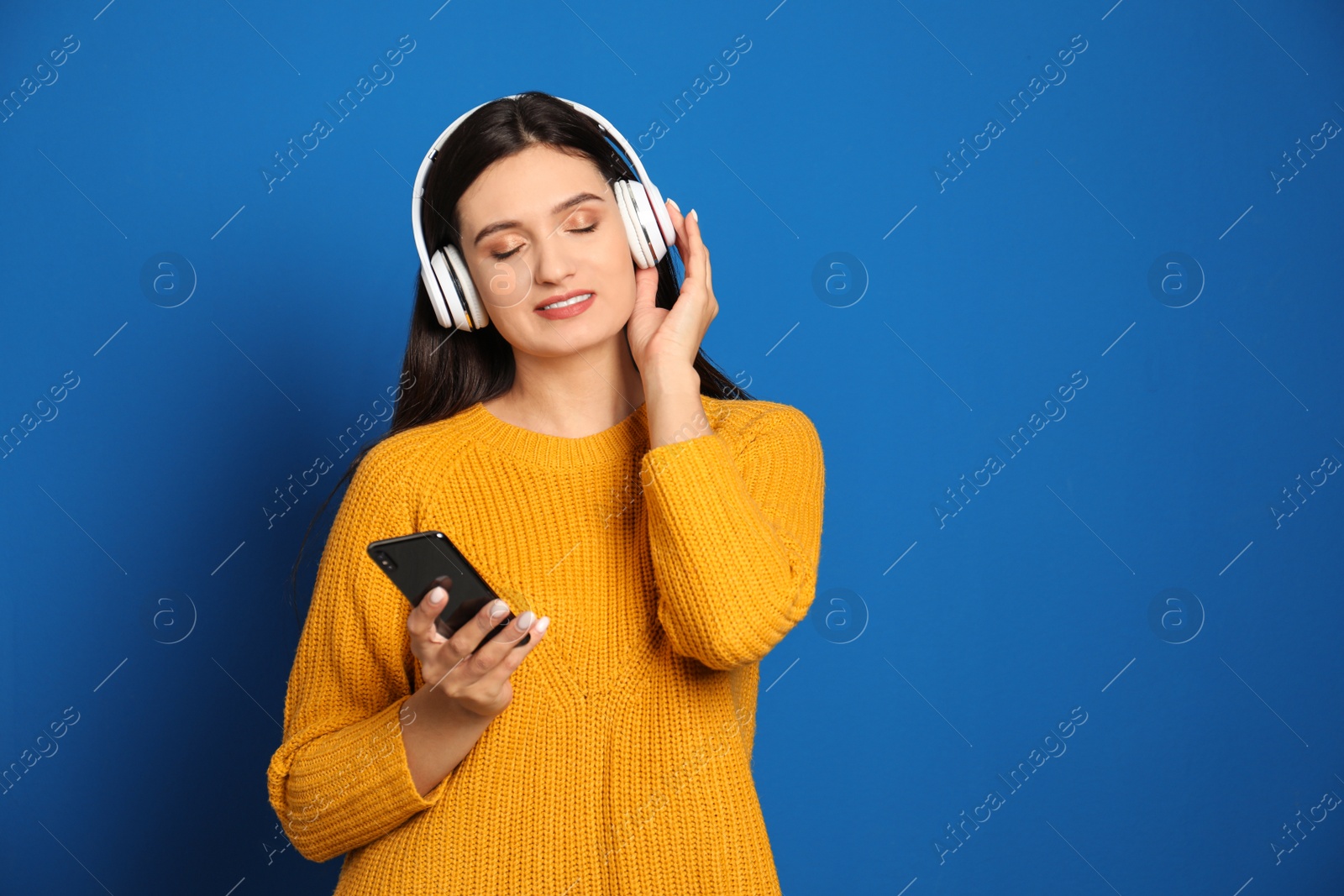 Photo of Young woman listening to audiobook on blue background. Space for text