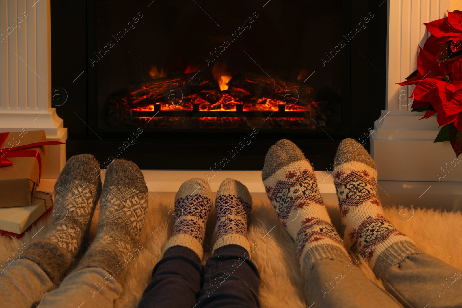 Photo of Lovely family in warm socks resting near fireplace at home, closeup