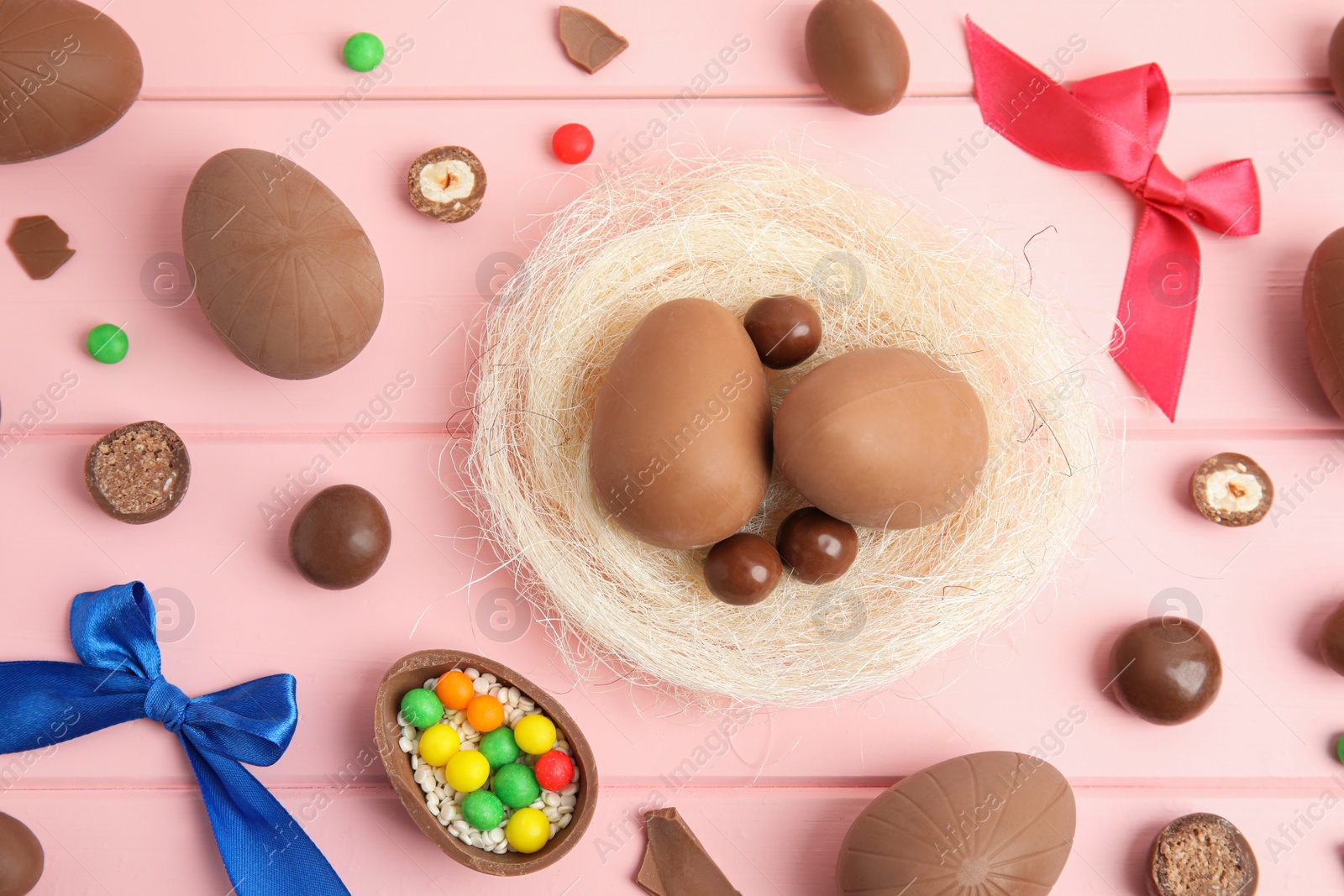 Photo of Flat lay composition with delicious chocolate Easter eggs on pink wooden table