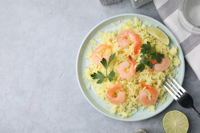 Photo of Delicious risotto with shrimps, lime and parsley on light grey table, flat lay. Space for text