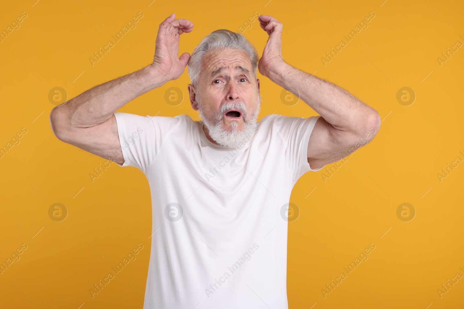 Photo of Portrait of surprised senior man on yellow background
