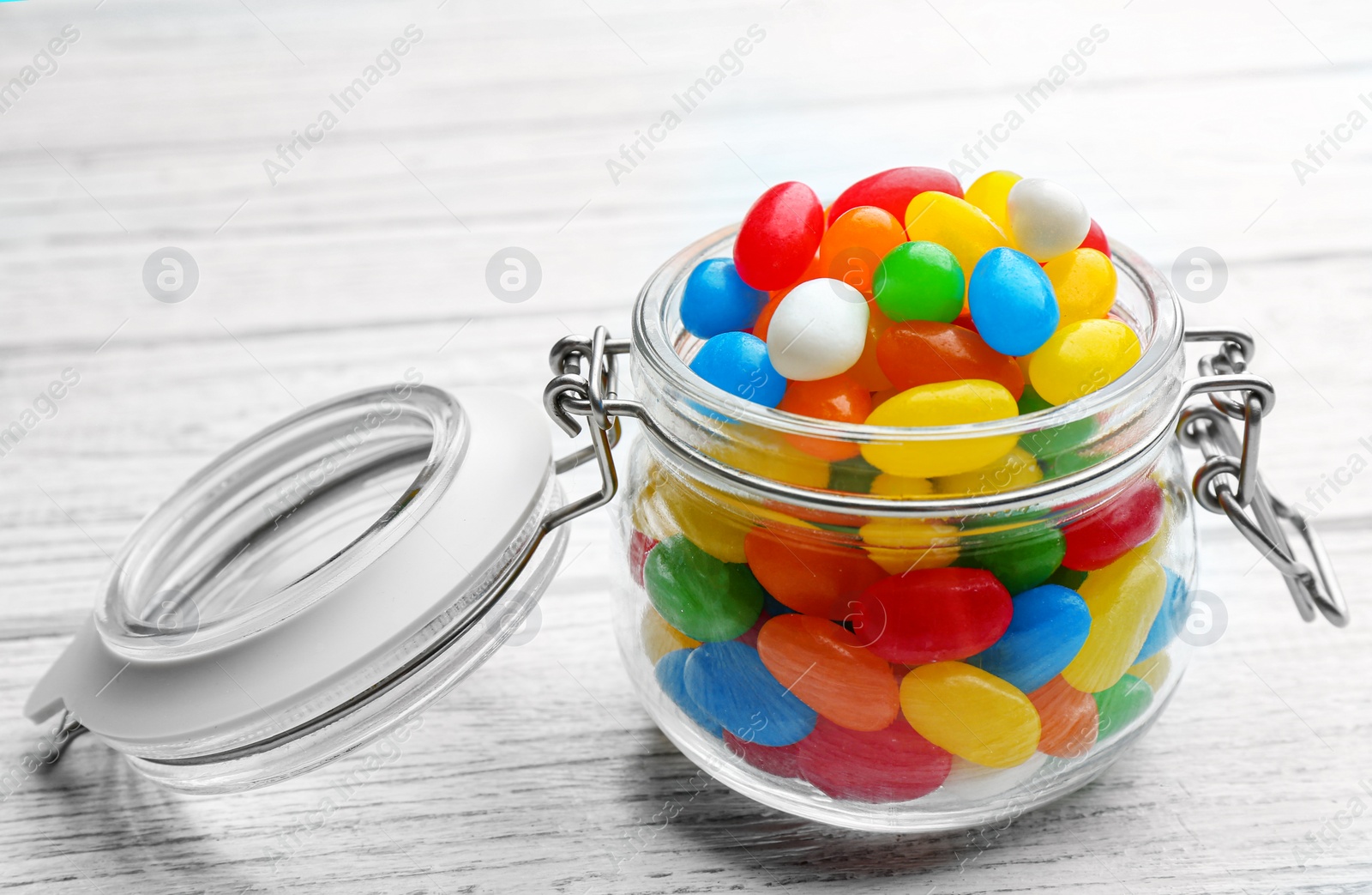 Photo of Jar with colorful jelly beans on white wooden background