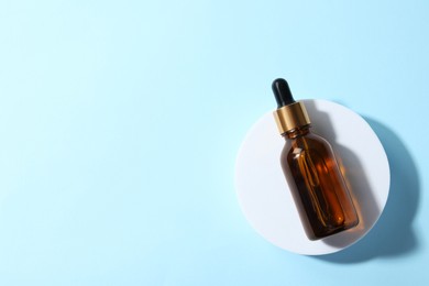 Bottle of cosmetic oil on light blue background, top view. Space for text