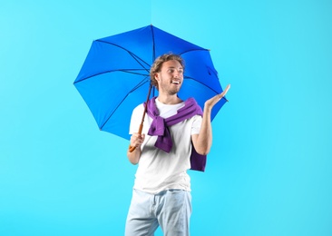 Man with blue umbrella on color background