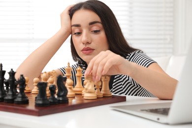 Unhappy young woman playing chess with partner through online video chat at home