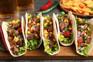 Photo of Delicious tacos with meat and vegetables on table, closeup