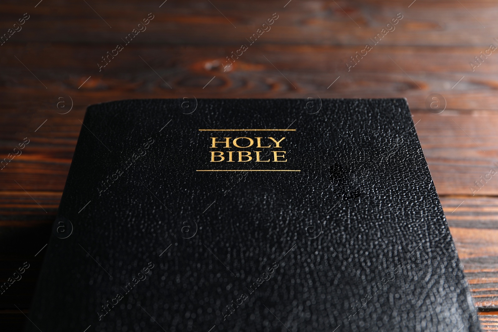 Photo of Bible with black cover on wooden table., closeup Christian religious book