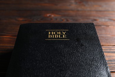 Bible with black cover on wooden table., closeup Christian religious book