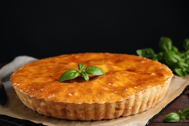 Delicious pie with meat and basil on wooden table