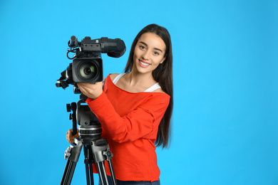 Operator with professional video camera on blue background