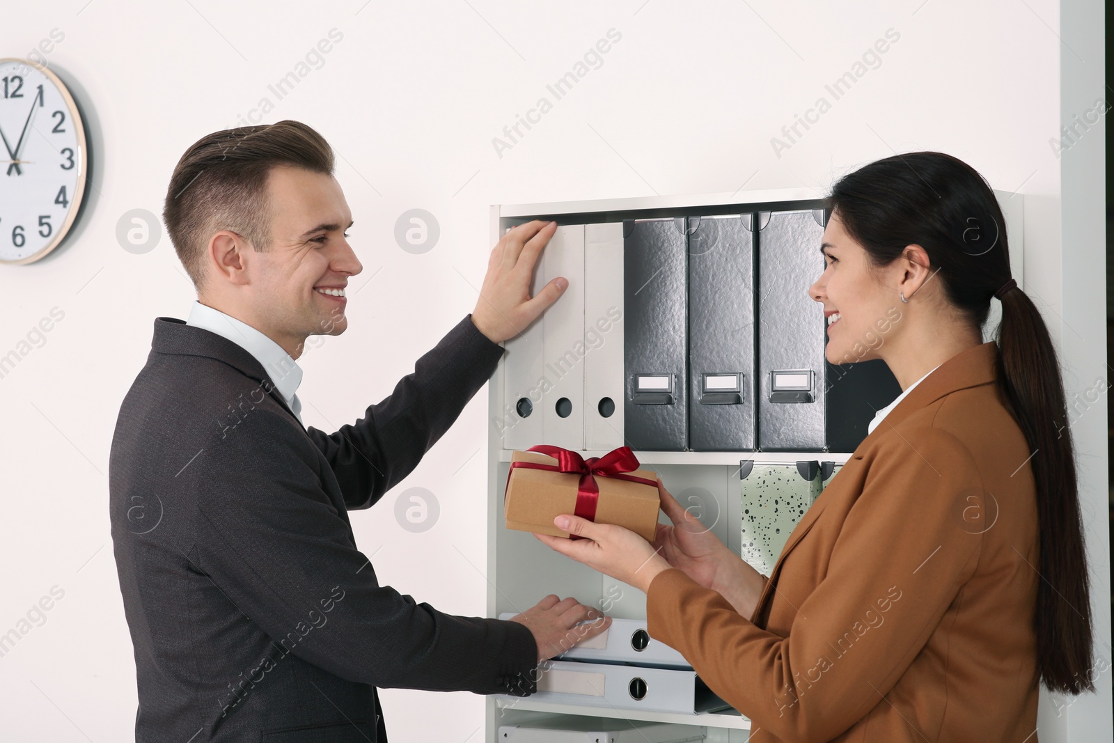 Photo of Woman presenting gift to her colleague in office