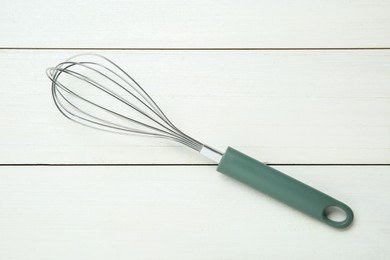 Photo of Metal whisk on white wooden table, top view