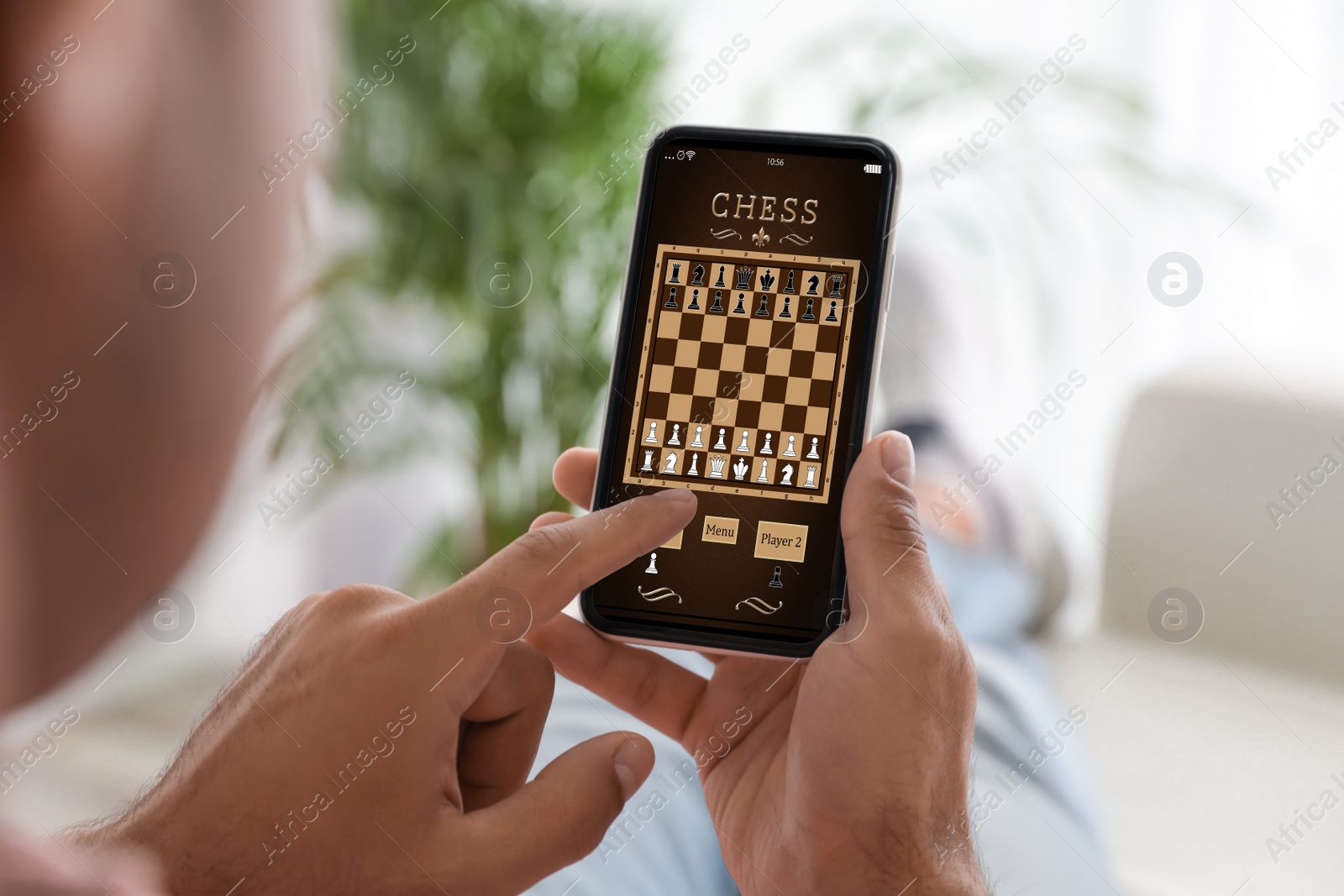 Image of Man playing online chess on smartphone indoors, closeup