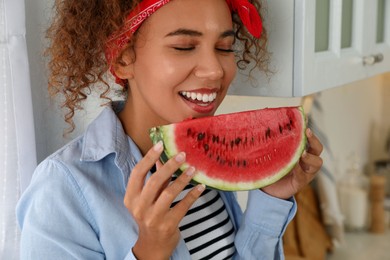 Photo of Beautiful young African American woman with slice of watermelon in kitchen at home, closeup