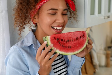 Beautiful young African American woman with slice of watermelon in kitchen at home, closeup