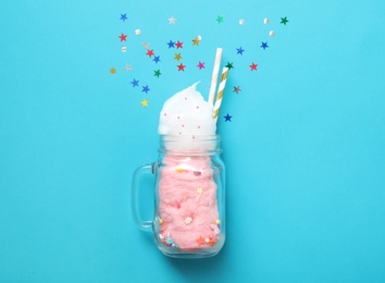 Mason jar with yummy cotton candy on color background, top view