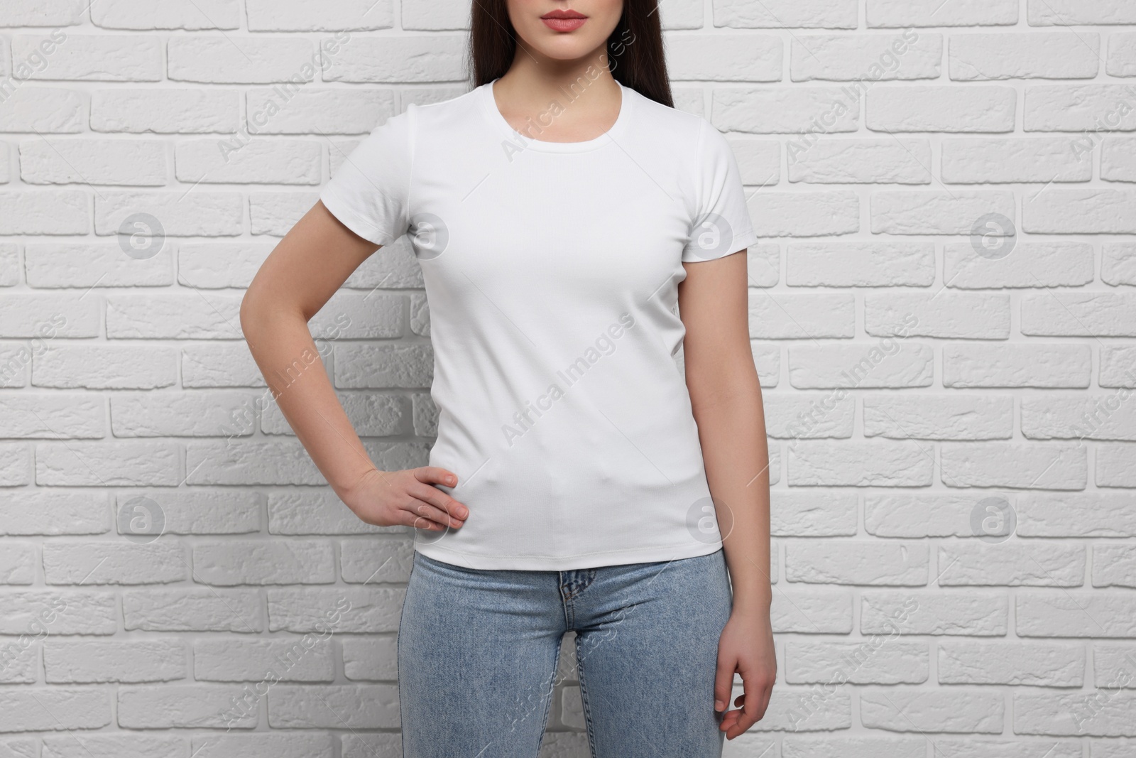 Photo of Woman wearing stylish T-shirt near white brick wall, closeup