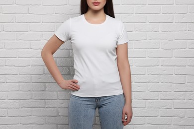 Woman wearing stylish T-shirt near white brick wall, closeup