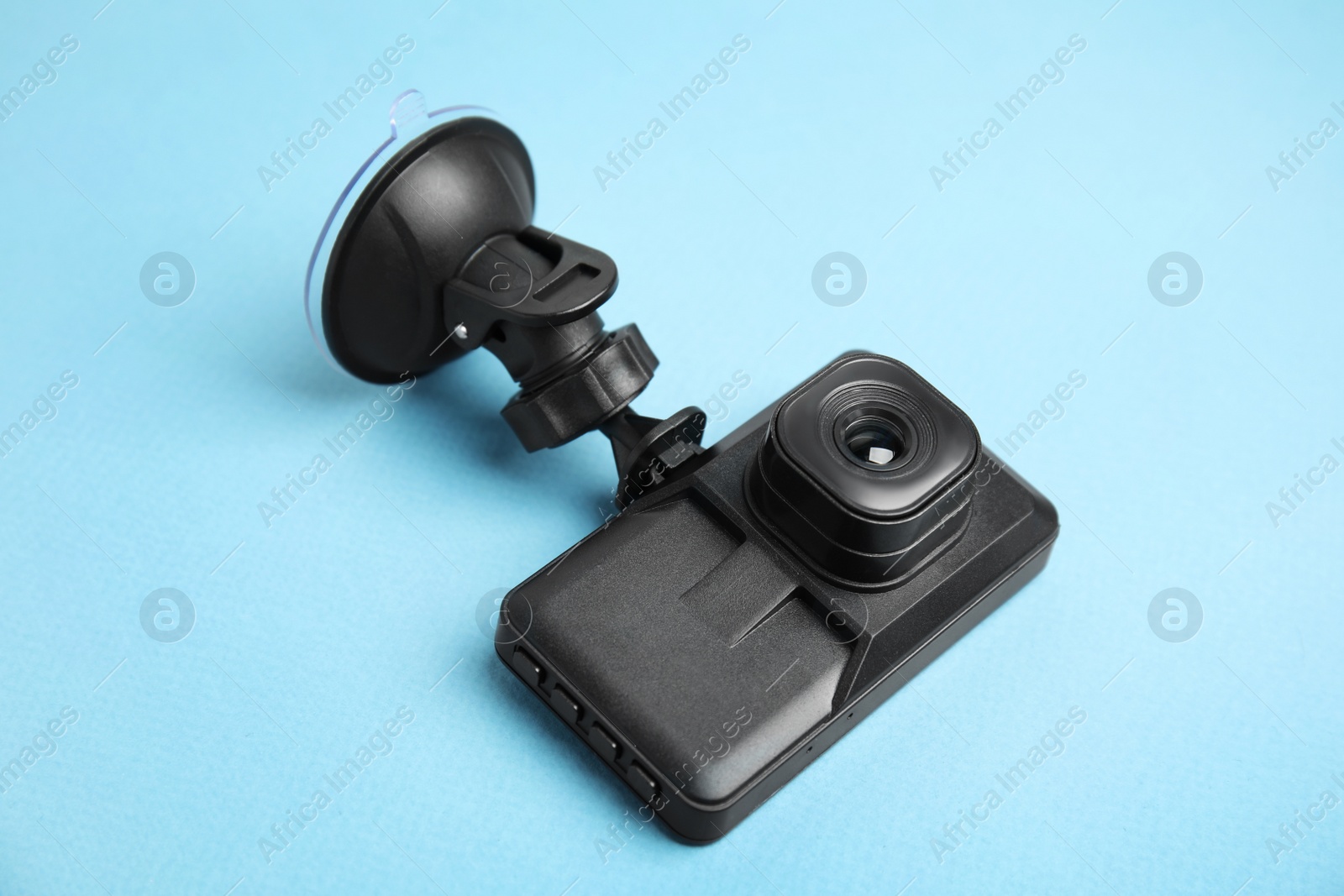Photo of Modern car dashboard camera with suction mount on light blue background