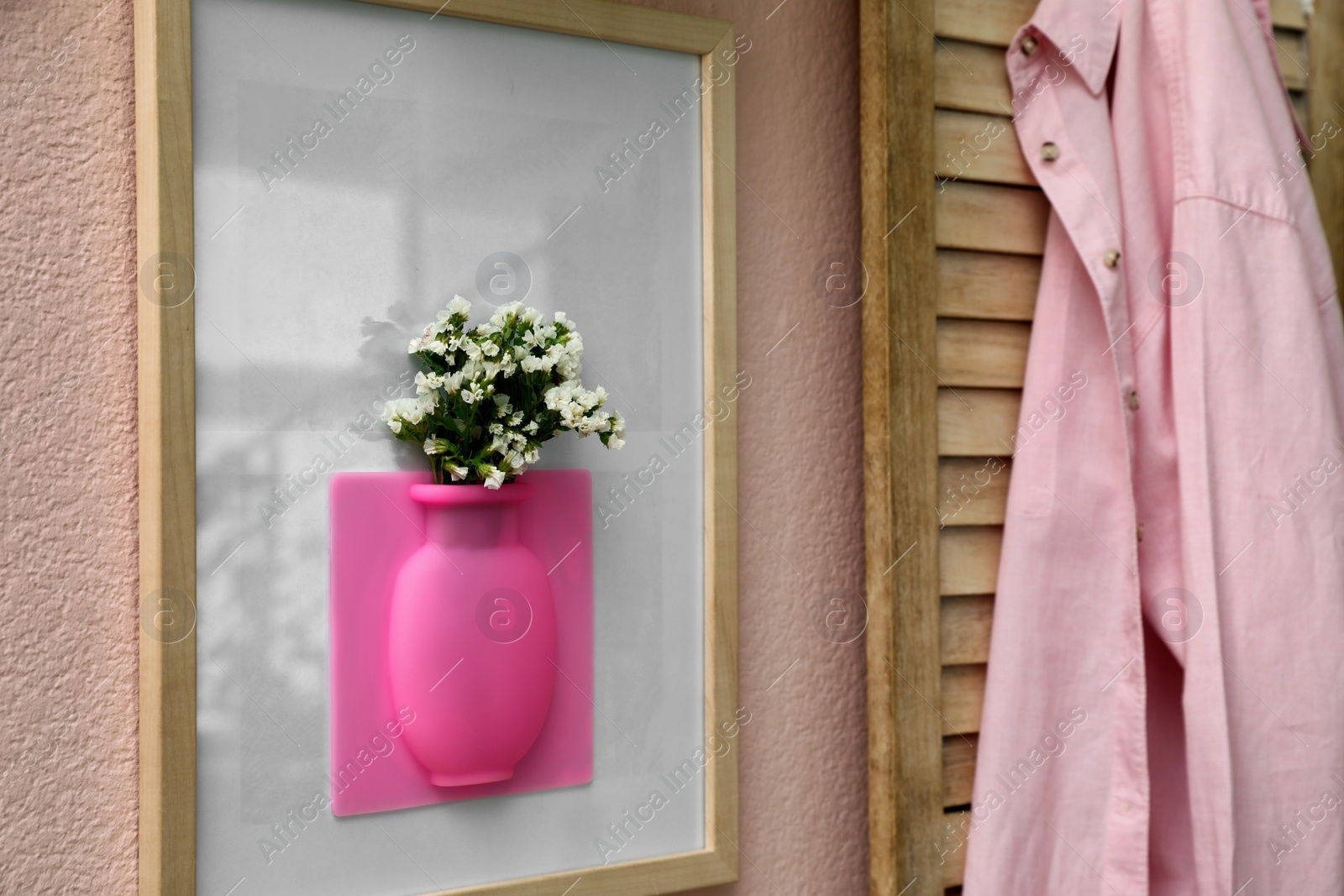 Photo of Silicone vase with beautiful white flowers on pink wall in room