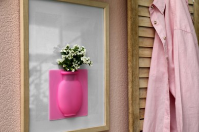 Silicone vase with beautiful white flowers on pink wall in room