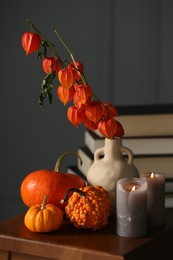 Beautiful autumn composition with pumpkins and burning candles on wooden table indoors