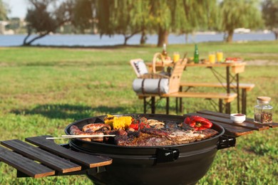 Photo of Tasty meat and vegetables on barbecue grill outdoors. Space for text