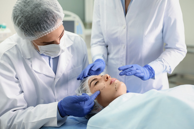 Photo of Doctor and nurse preparing female patient for cosmetic surgery in clinic