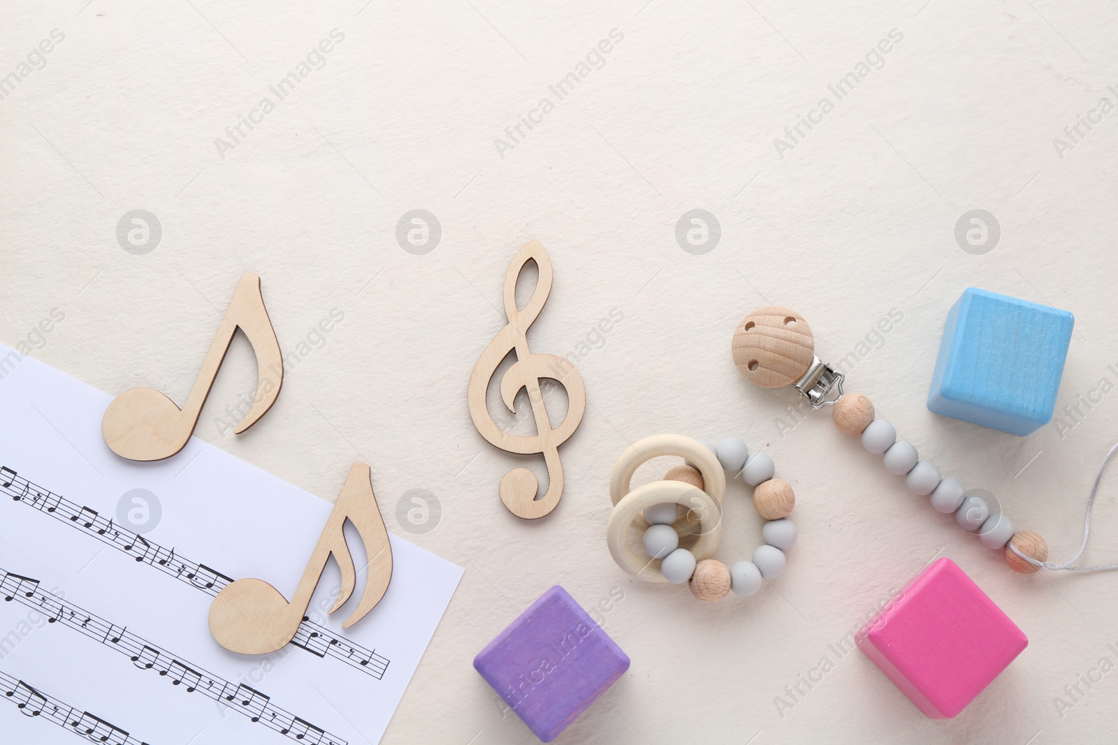 Photo of Wooden notes, music sheet and toys on beige background, flat lay with space for text. Baby song concept