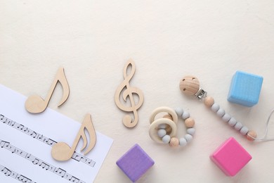 Wooden notes, music sheet and toys on beige background, flat lay with space for text. Baby song concept