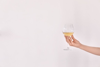 Woman holding glass of wine on light background