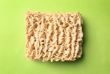 Photo of Block of quick cooking noodles on color background, top view