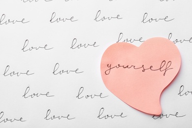 Composition with words LOVE YOURSELF and paper heart on white background, top view