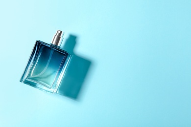 Bottle of perfume on color background, top view