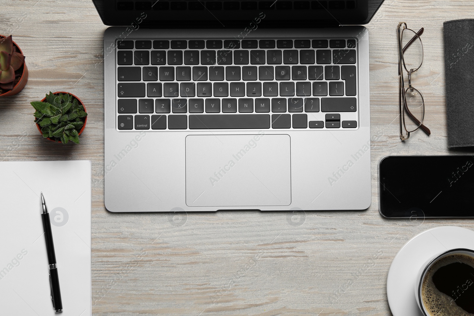 Photo of Modern laptop, houseplants, notebook, cup of coffee and glasses on wooden table, flat lay